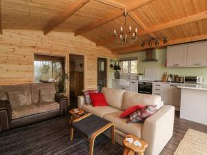 a living room with a couch and a kitchen at The Cabin in Garnant