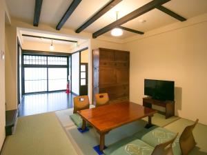 Una sala de estar con una mesa de madera y un televisor. en Nijo Yurakuan, en Kioto