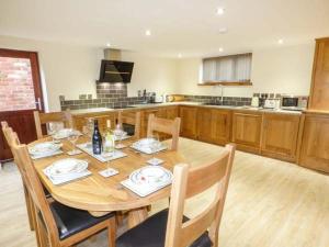 Manor Barn في Fulford: مطبخ مع طاولة خشبية مع كراسي وطاولة بجانب السرير