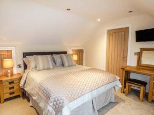 Manor Barn في Fulford: غرفة نوم بسرير كبير ومكتب خشبي