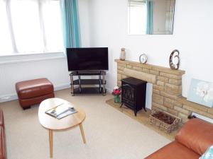 a living room with a television and a fireplace at Kate's Cottage in Bourton on the Water