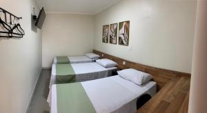 two beds in a room with white walls at Hotel Casa Grande in Pôrto Ferreira