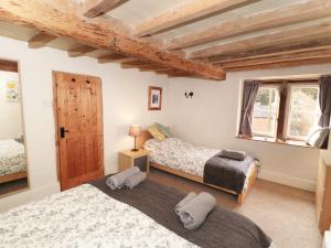 a bedroom with two beds and a wooden ceiling at Holly Cottage in Matlock