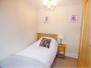 a bedroom with a bed and a table with a lamp at Mill Cottage in Wolsingham