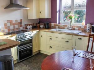 a kitchen with white cabinets and a wooden table at Primrose Cottage in Alford