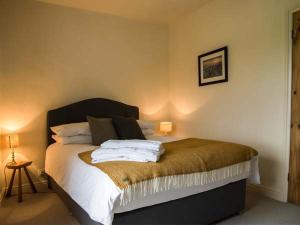 a bedroom with a bed with white sheets and pillows at Beacon Cottage in Ilkley