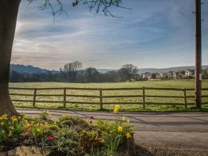 a fence next to a road with flowers and a field at Beacon Cottage in Ilkley