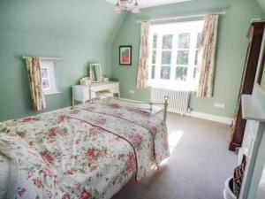 a bedroom with a bed with a floral bedspread at The Gate House in Oakamoor