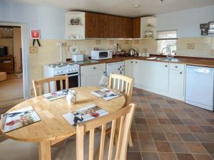 a kitchen with a wooden table and chairs and a kitchen with white appliances at Church View in Hartington
