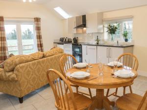 a kitchen and dining room with a table and a couch at Millstone Cottage in Westbury