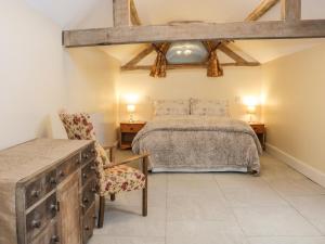 a bedroom with a bed and two chairs and a table at Millstone Cottage in Westbury