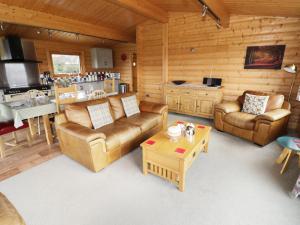 a living room with leather furniture and a kitchen at Look Out Lodge in Little Witley