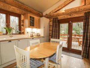 uma cozinha e sala de jantar com uma mesa de madeira e cadeiras em Moorhen Lodge em Inverness