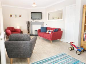 una sala de estar con 2 sillas y una silla roja en The Beach House Criccieth, en Criccieth