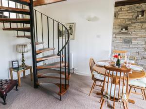 una sala da pranzo con scala a chiocciola e tavolo di Barn Cottage a West Burton