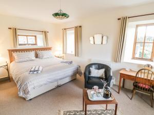 West BurtonにあるBarn Cottageのベッドルーム1室(ベッド1台、椅子、テーブル付)