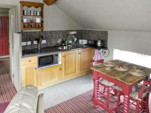 a kitchen with a table and a sink and a microwave at The Hayloft in Lastingham