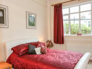 ein Schlafzimmer mit einem Bett mit roten Laken und einem Fenster in der Unterkunft The Cabin in Ilfracombe