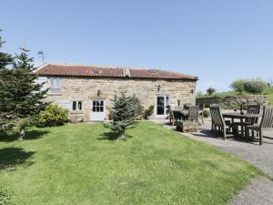 a stone cottage with a table and chairs in the yard at Swallow Cottage in Scarborough
