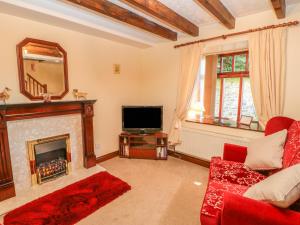 a living room with a fireplace and a tv at Garden Cottage in Mickleton
