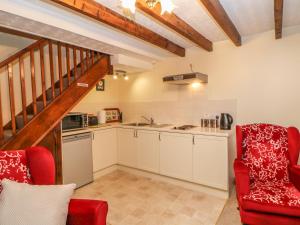 a kitchen with white cabinets and a red chair at Garden Cottage in Mickleton
