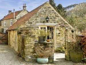 une maison en pierre avec des plantes en pot devant elle dans l'établissement Beckside, à Lastingham