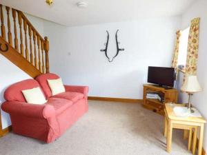 ピカリングにあるStable Cottageのリビングルーム(赤い椅子、テレビ付)