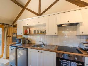 a kitchen with white cabinets and a sink at The Byre in Highley