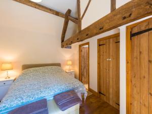 Schlafzimmer mit einem Bett und Holzbalken in der Unterkunft The Byre in Highley