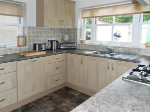 a kitchen with wooden cabinets and a sink and windows at River Cottage in Staithes