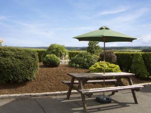 una mesa de picnic con una sombrilla y un banco en The Loft, en Annan