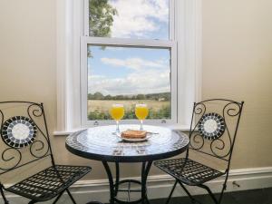 two glasses of orange juice sitting on a table in front of a window at Riverside View in Grange Over Sands