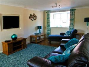 Una sala de estar con un sofá de cuero y un televisor. en Water's Edge, en Whitby 6 fotos más