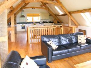 a living room with a black leather couch and a kitchen at Shepherd's Hut in Blandford Forum