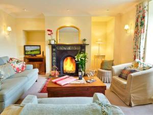 a living room with a couch and a fireplace at The Old Farmhouse in Bowsden