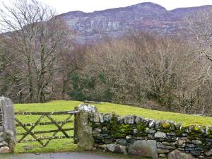 a stone fence in front of a grassy field at Y Bwthyn in Llanbedr