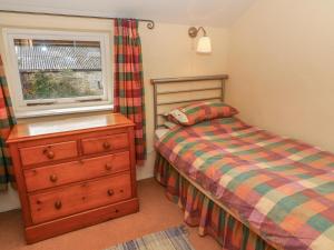 a bedroom with a bed and a dresser and a window at The Granary in Kirkby Lonsdale