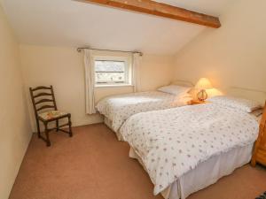 Duas camas num quarto com uma cadeira e uma janela em The Granary em Kirkby Lonsdale