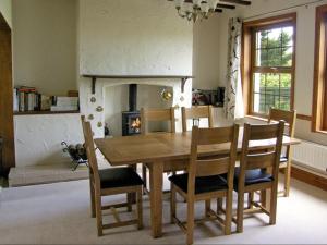 ein Esszimmer mit Tisch und Stühlen und einem Kamin in der Unterkunft Railway Cottage in Fairbourne