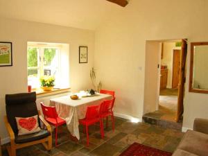 a dining room with a table and red chairs at Stone Cottage in Mold