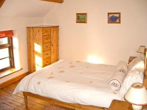 a bedroom with a white bed and a window at Tailor's Cottage in Abbey-Cwmhir