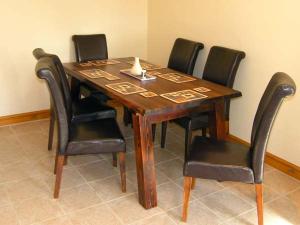 un tavolo in legno con sedie nere intorno di Farmhouse Cottage a Pentraeth