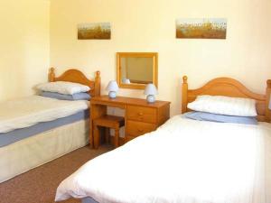 a bedroom with two beds and a table with a mirror at Farmhouse Cottage in Pentraeth