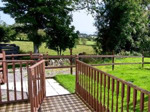 una recinzione di legno con una passerella che conduce a un campo di Farmhouse Cottage a Pentraeth