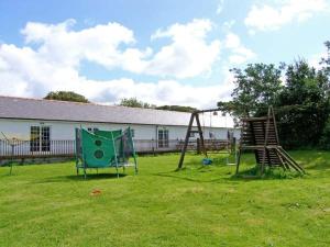 einen Hof mit einer Schaukel und einem Spielplatz in der Unterkunft Farmhouse Cottage in Pentraeth