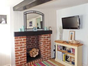 a living room with a brick fireplace with a mirror at Little Thatch in Walton-on-the-Naze