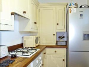 a kitchen with a stove and a white refrigerator at Little Thatch in Walton-on-the-Naze