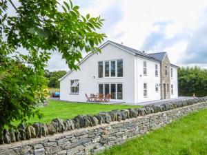 a large white house with a stone wall at Chapel House in Llantrisant