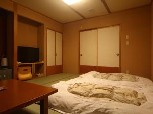 1 dormitorio con 1 cama grande y TV en Kamihoroso, en Kami-furano