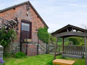 a brick house with a bench and a gazebo at The Granary in Craven Arms